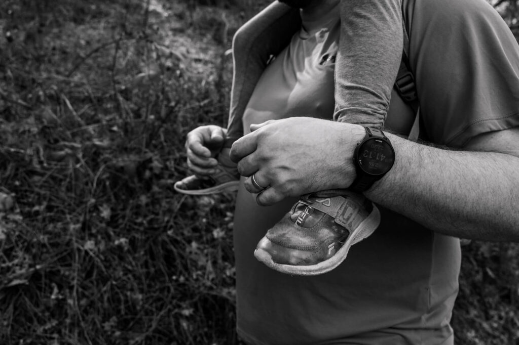 The legs of a little girl draped over the shoulders of her dad as he gives her a piggy back ride, with his arms around her legs