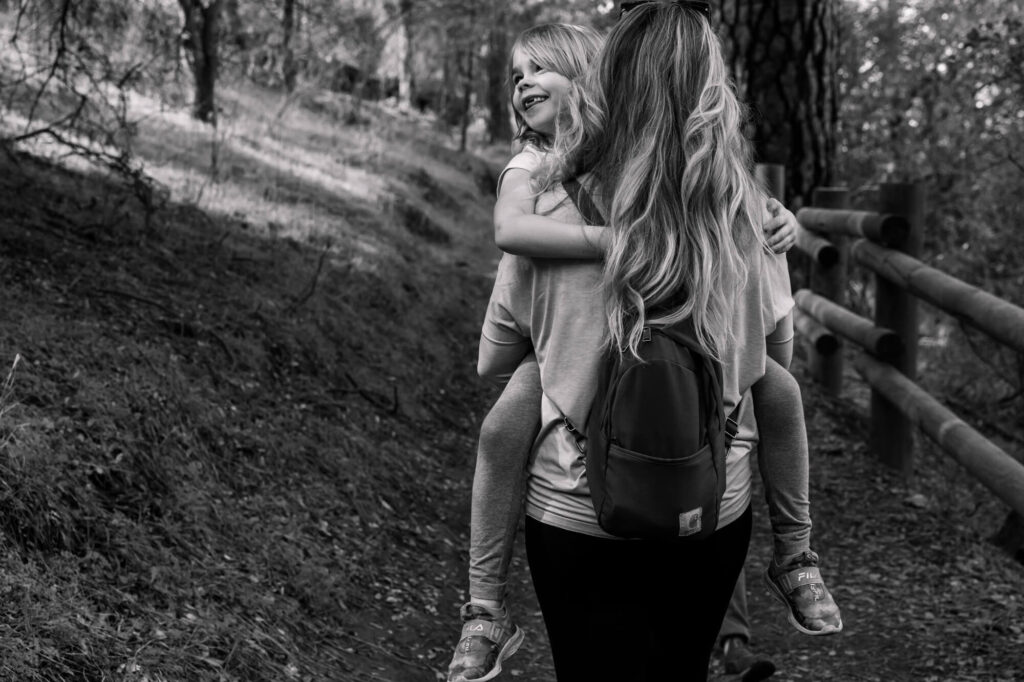 Mom carrying daughter on a nature trail returning on the Hidden Falls trail