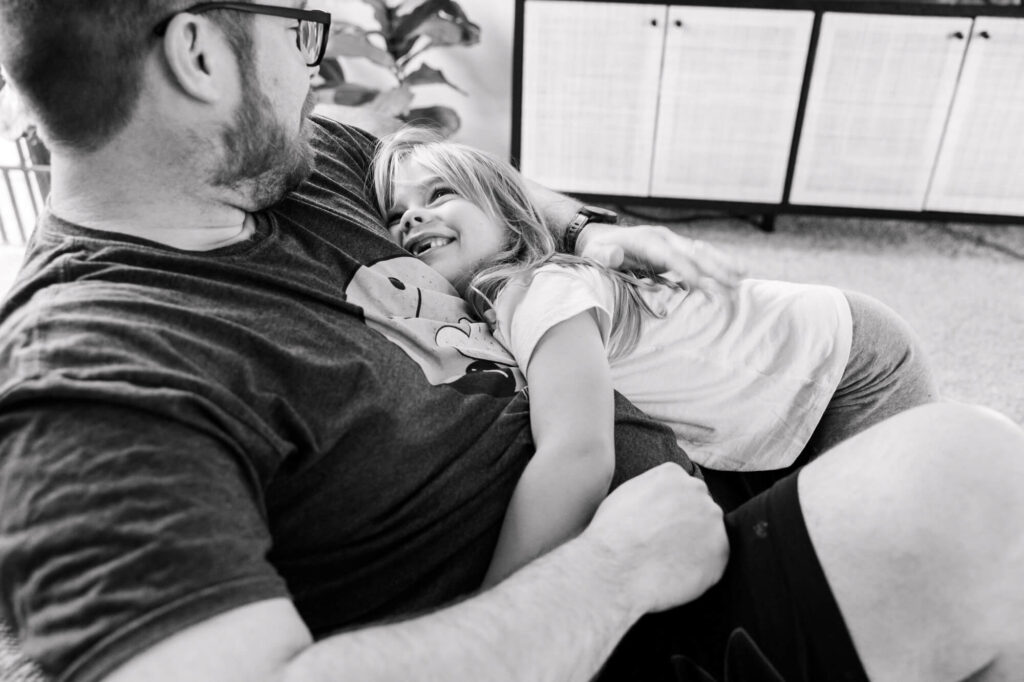 Daughter snuggling on dad's chest as they both look at each other